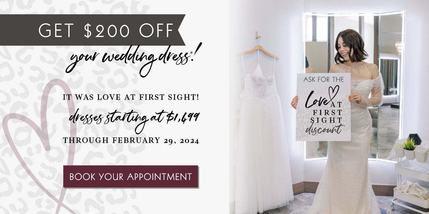 Save $200 on your wedding dress through Feb 29, 24. Bride in long sleeve sparkle Sincerity gown standing in well lit bridal suite